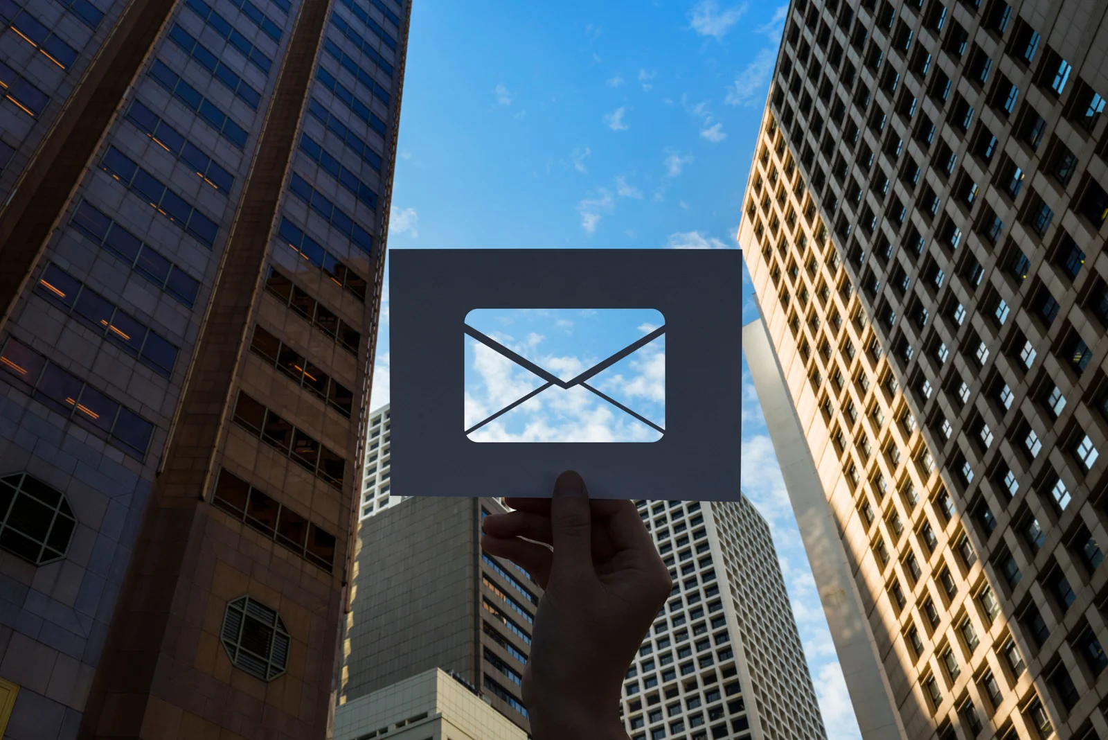 Ruka se symbolem e-mailu mezi výškovými budovami