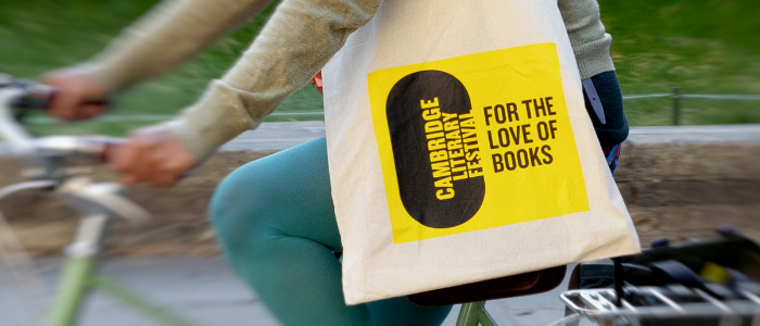 Person riding a bicylce with a Cambridge Literary Festival branded tote bag